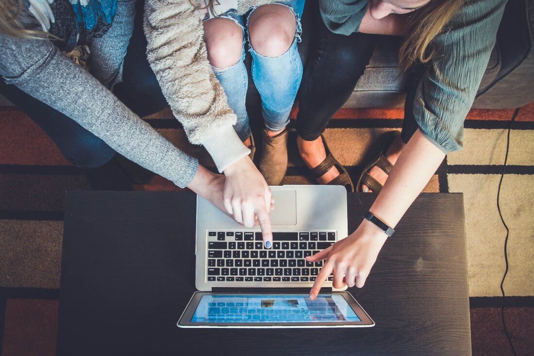 A group of hybrid workers around a laptop communicating