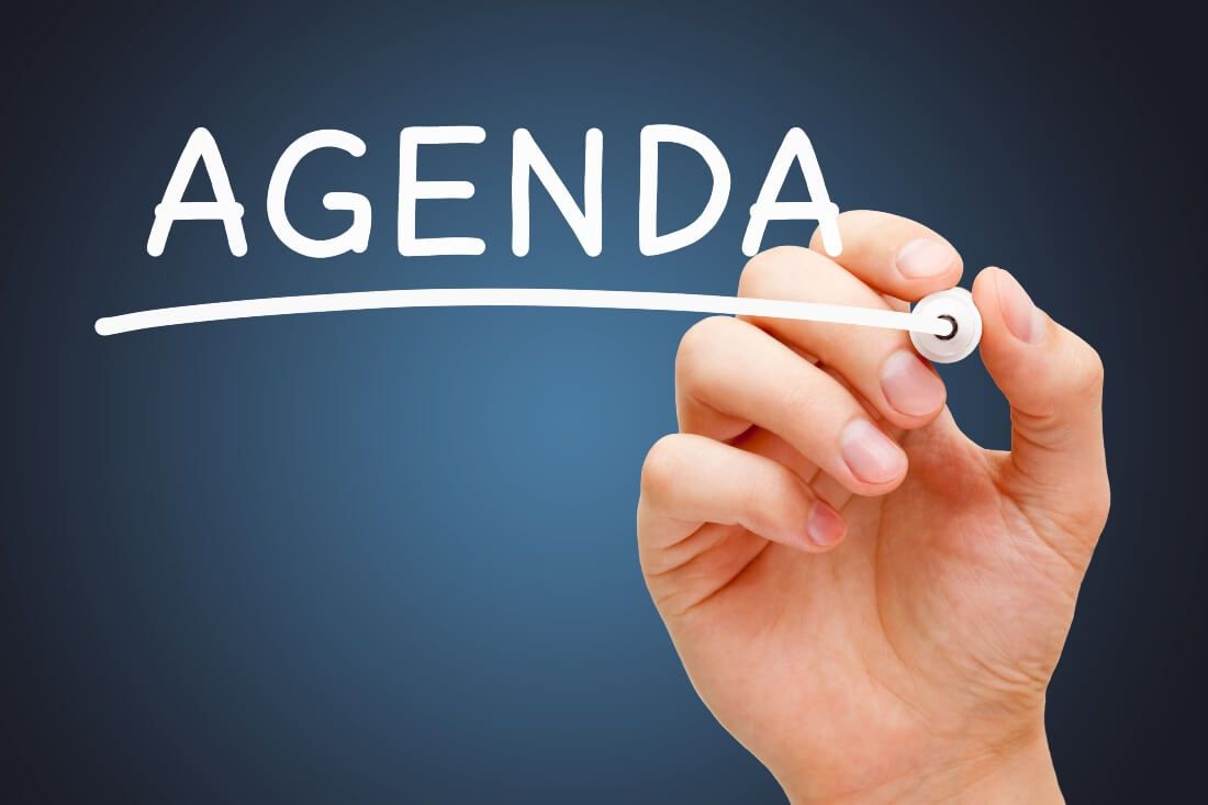 a picture of a hand writting the word agenda